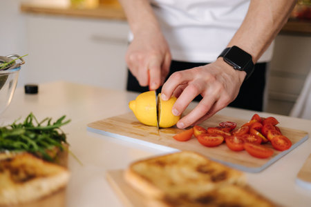 Close-up of male slice fresh lemon on wooden boardの写真素材