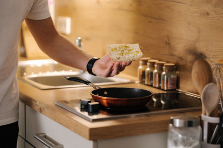 Human hands put slice of baguette on the heated pan. Home made food conceptの写真素材