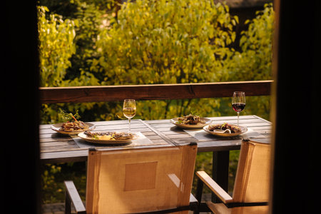 Outdoor dinner on summer terrace. Served table with several dishes. Tasty food in restaurant. View from insideの写真素材