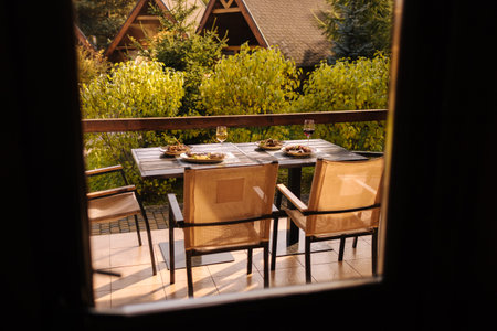 Outdoor dinner on summer terrace. Served table with several dishes. Tasty food in restaurant. View from insideの写真素材