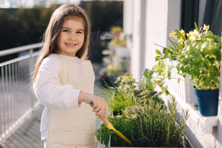 Cute little girl starting for landing on balcony. Side view of four year old girl use small shovel for soilの写真素材