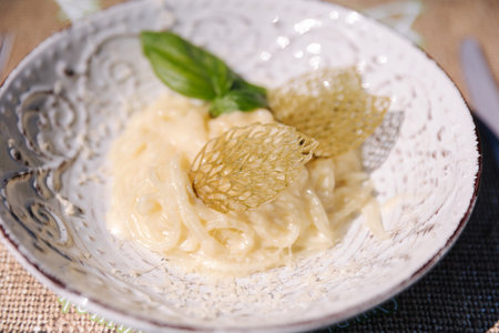 Cheese pasta with a creamy sauce with a leaf of basil