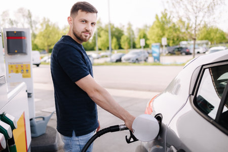 Handsome man refuelling his car on self service gas station. Male filling diesel at gasoline fuel in car using a fuel nozzle. Petrol concept.の写真素材
