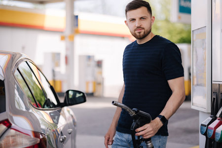 Handsome man refuelling his car on self service gas station. Male filling diesel at gasoline fuel in car using a fuel nozzle. Petrol concept.の写真素材