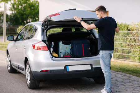 Side view of handsome man close hatchback car for trunk. Vehicle and automotive travel road trip. Holliday on summer vacation conceptの写真素材