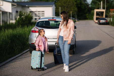 Adorable daughter with her mom go to airport with suitcases. Two girls goes to a trip. Little girl travel with mom.の写真素材