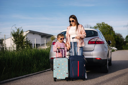 Mom and daughter stand near the car with their suitcases and waiting for the trip. Family journeyの写真素材