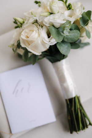 Wedding bouquet and vows on chair. White roses and eucalyptus. Beautiful fresh flowers. Bride morning conceptの写真素材
