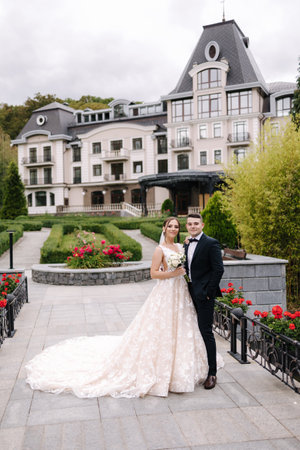 Beautiful bride and groom stand in front of luxury building. Newlyweds go to restaurant to celebrate weddingの写真素材