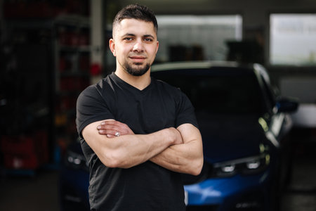 Portrait of handsome male owner of car repair shop. Bearded mechanic at work in his garageの写真素材