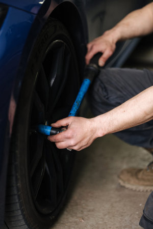 Close-up of mechanic change tires on a car near his garage. Woking outdoors. High quality photo