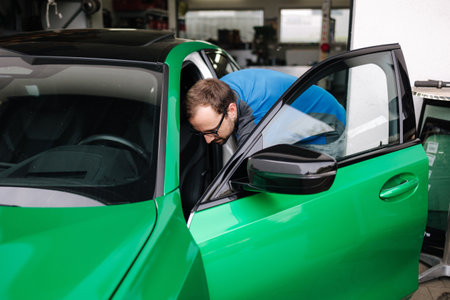 Man auto mechanic presses the button to open the hood of the car for inspectionの写真素材