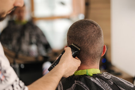 Back view of human hand hold trimmer and make hairstyle for man. Barbershopの写真素材
