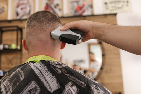 Rear view shot of hairdresser cutting hair of male client. Barber shop