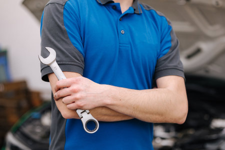 Middle selection of male mechanic hold auto repair tool. Man stand in front of car with open hoodの写真素材