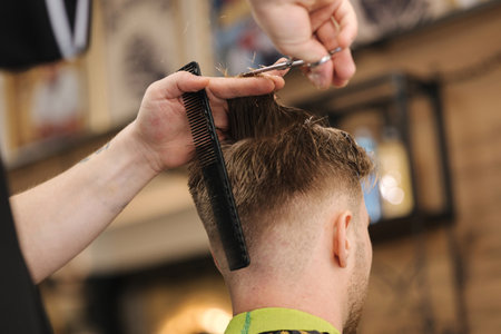 Back view of barber using scissors and making hairstyle. Modern barbershopの写真素材