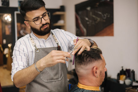 Side view of barber using scissors and making hairstyle. Modern barbershopの写真素材