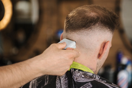 Back view of human hand hold trimmer and make hairstyle for man. Barbershopの写真素材