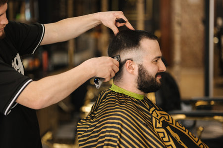 Side view of Professional barber cutting hair of his client.の写真素材