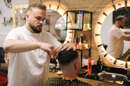 Hairdresser cutting hair using scissors and comb. Professional barber serves the clientの写真素材