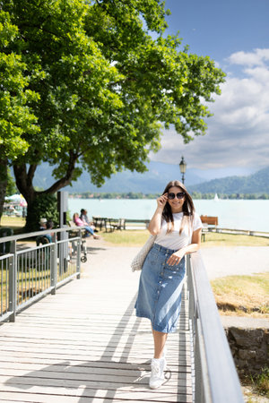 Elegant woman in denim skirt walking though the little bridge and smile. Stylish female. High quality photoの写真素材