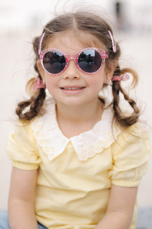 Close-up portrait of beautiful little girl in sunglasses. Happy kidの写真素材