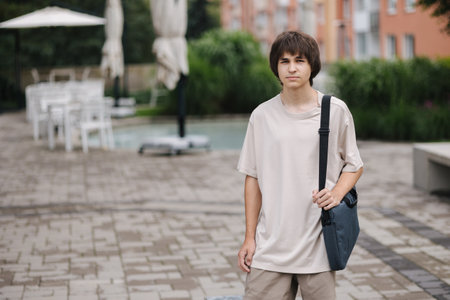 Portrait of teenage boy student with laptop bag go home after collegeの写真素材