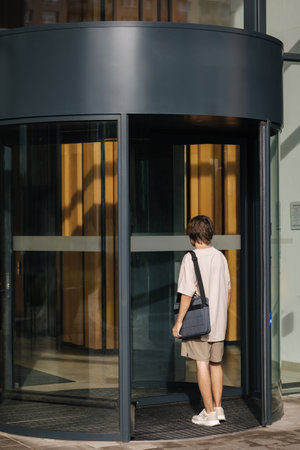 Back view of young delivery boy come inside the business centre for delivery documentsの写真素材