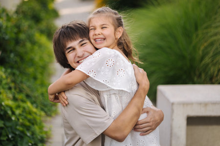 Portrait of happy and beautiful sister with her cousin. Adorable little girl and handsome teenage boyの写真素材