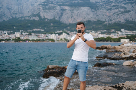 Photo of a young man taking a photo on his phone of a photographer taking a photo of himの写真素材