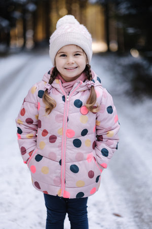 Happy little girl walking in snowy winter forest. Near year moodの写真素材