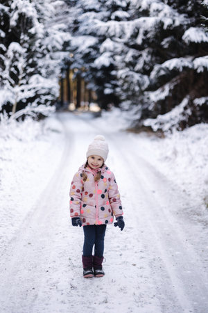 Adorable little girl in big snowy forest. Happy childhoodの写真素材