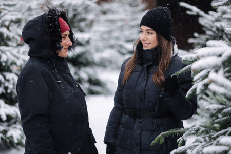 Portrait of mom and daughter choose fir tree for Christmas holidaysの写真素材