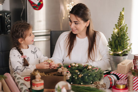 Mom and daughter making Christmas wreath using fresh pine branches and festive decorations. Christmas moodの写真素材
