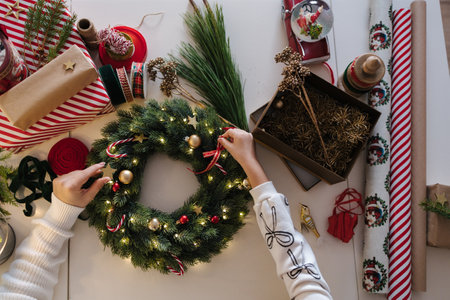 Top view of mom and daughter decorating Christmas wreath. Process of home made winter decorの写真素材