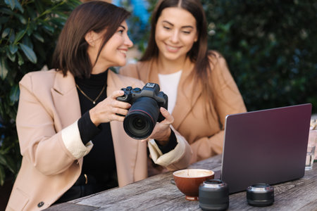 Photographer show to client photos on camera. Happy females slime and checking photos. Focus on camera. Workspaceの写真素材