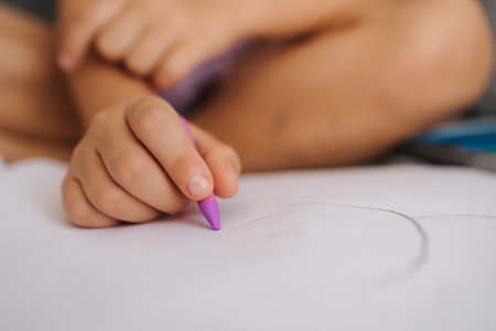 Close-up of little girls hand with pencil. Five year old girl drawing at home after kindergarten. Magenta colorの写真素材