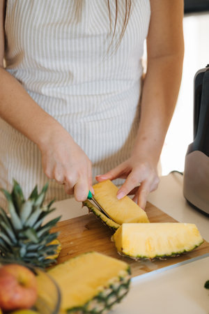 Close-up of female peel ananas on wooden table.の写真素材