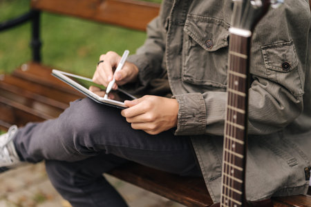 Close-up of boy painting in tablet using pencil. Young designer using tablet outdoor. Spring time....