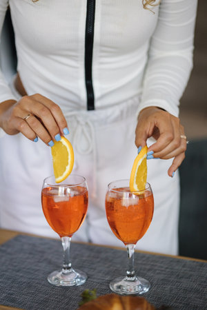 Close-up of attractive curly hair girl preparing cocktail at home. Food and drinks on wooden tableの写真素材