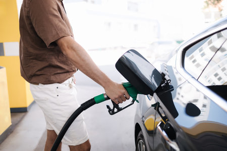 Handsome young man refueling car at gas station. Petrol concept. Side view. Middle selection. Fuel price increaseの写真素材