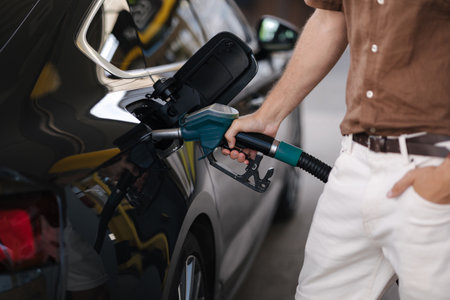 Close-up of human hand pumping gasoline car with fuel at the refuel station. Driver refueling the car at a gas station. Benzine. Fuel price increaseの写真素材