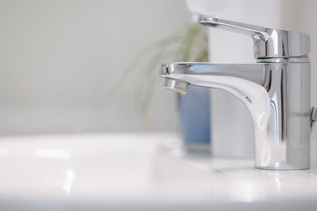A drop of water on the faucet. No water. White tile and sensor dispenser. Close-upの写真素材