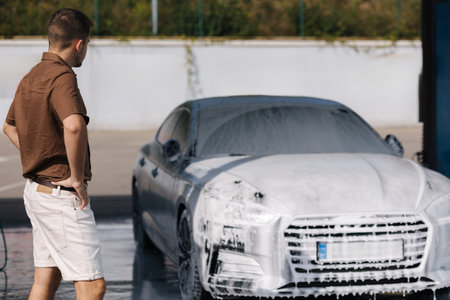 Man stand in front of his luxury car all in white foam on self service car wash. Waitingの写真素材