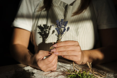 Female hand uses natural twine to tie lavender sprigs. Preparing fresh herbs for dryingの写真素材