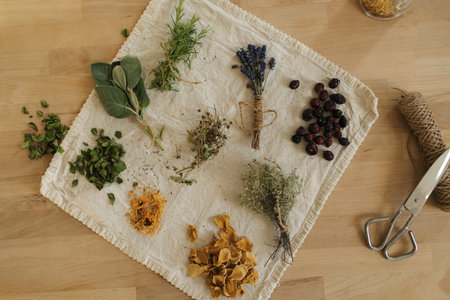 Top view of different dried herbs on linen tablecloth. Wooden table scissors, natural twine.