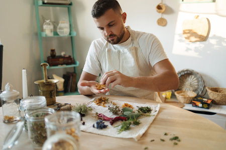 Handsome man in an apron sits at the table and preparing healthy and nutrition herbal tea. High quality photoの写真素材