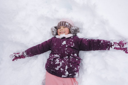 Little girl covered in snow, laughing and playing. A perfect scene of childhood excitement in a winter wonderland. Snow starの写真素材