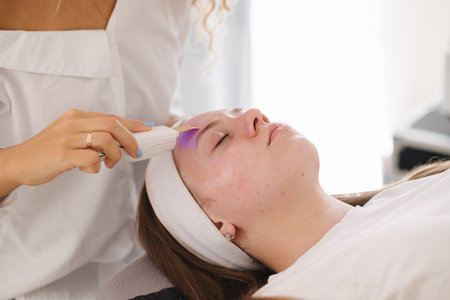 A professional skincare specialist applies a cooling gel on a clients face with a gentle spatula, focusing on precise treatment.の写真素材