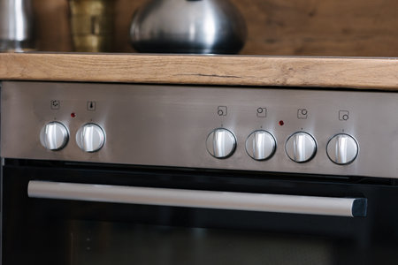 Control panel of an oven with silver knobs in a stylish kitchen.の写真素材